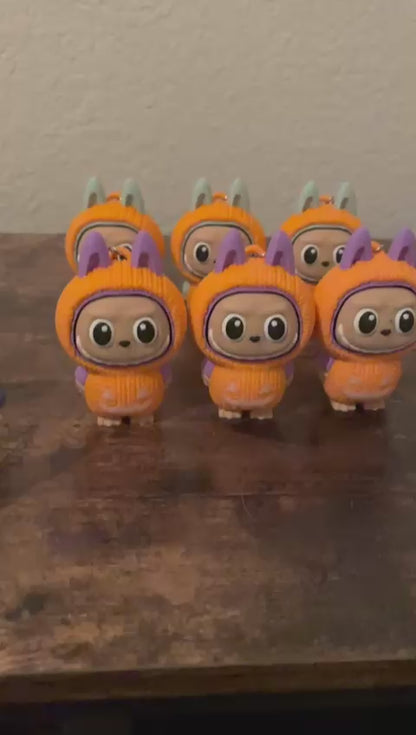 Limited edition Halloween Labubu fidget toy in a pumpkin onesie outfit with jack-o’-lantern details. Cute collectible figure with a clicky face feature, designed for Halloween season décor, stress relief, and toy collectors.